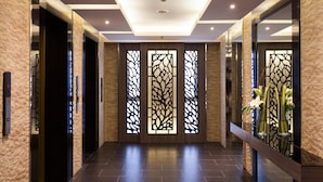 A modern hallway with a stone wall, a glass door, and a decorative screen with a floral pattern. - Grand 5 Hotel & Plaza Sukhumvit Bangkok (Bangkok)