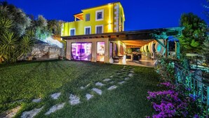 Une maison moderne à deux étages, dotée d’un éclairage extérieur soigné et d’un espace extérieur aménagé avec des sièges.