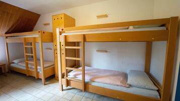 Ein Schlafsaalzimmer mit Etagenbetten, Holzmöbeln und Fliesenboden.