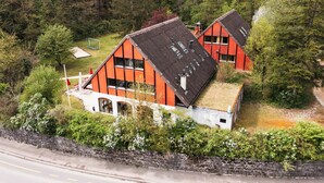 Ein Wohngebiet mit zwei Häusern mit roten Dächern, umgeben von Grünflächen, und einer Straße im Vordergrund.