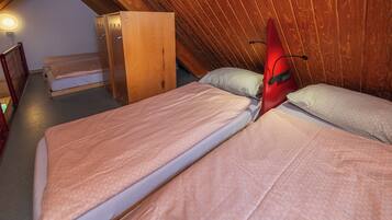 Ein kleines, gemütliches Zimmer mit zwei Einzelbetten, Holzwänden und einer geneigten Decke.