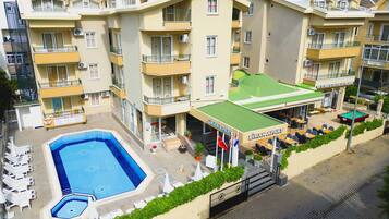 A multi-story hotel with a swimming pool, outdoor seating area, and balconies.