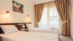 Een hotelkamer met twee bedden, een schilderij aan de muur en een raam met gordijnen.