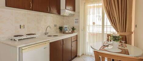 A compact kitchen with wooden cabinets, a built-in dishwasher, and a dining area with a table and chairs.