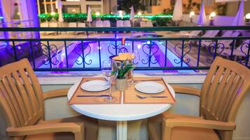 A dining table with two chairs, a bottle of champagne, and a small plant.