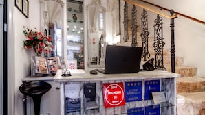 Un comptoir d’accueil avec un ordinateur portable, des photos encadrées et un panneau rouge indiquant une distinction Michelin.