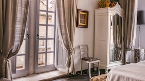 Une chambre à coucher avec un lit, une chaise, une armoire et une fenêtre avec des rideaux.