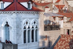 A historic building with a red-tiled roof, white stone facade, and arched windows.