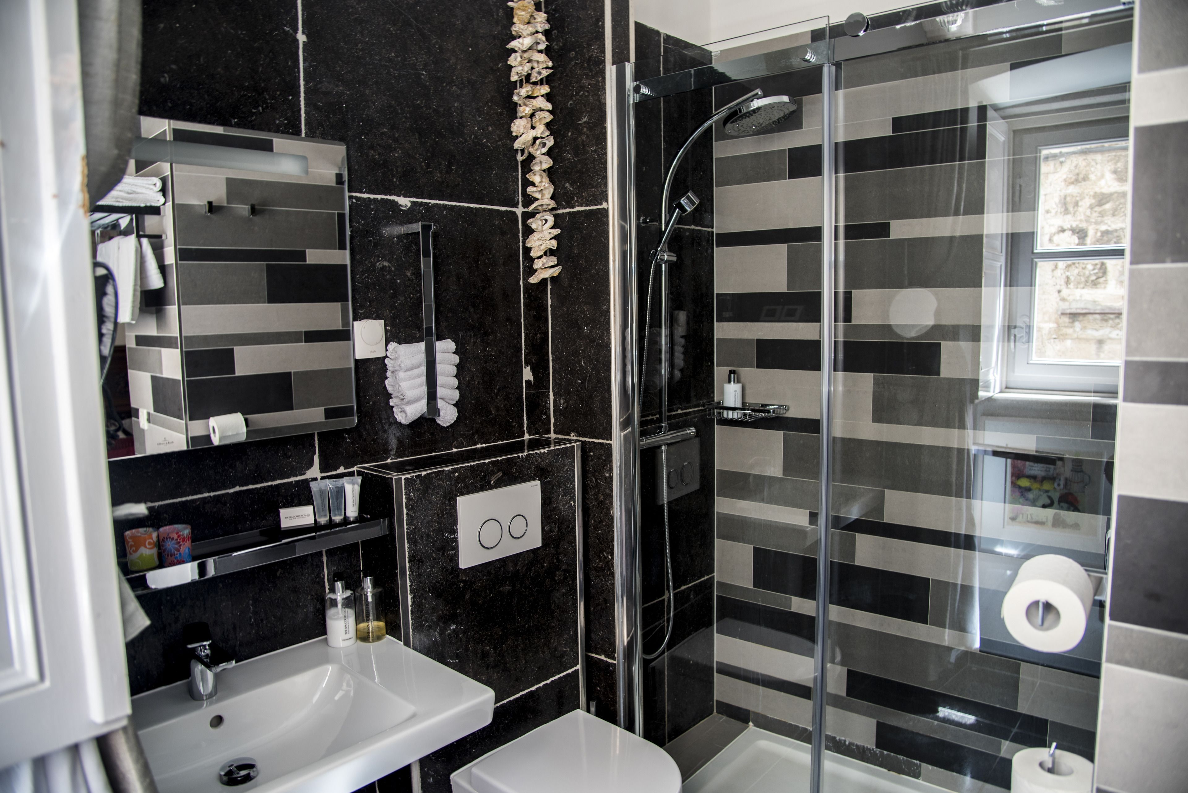A modern bathroom with a glass-enclosed shower, a white sink, and a toilet.