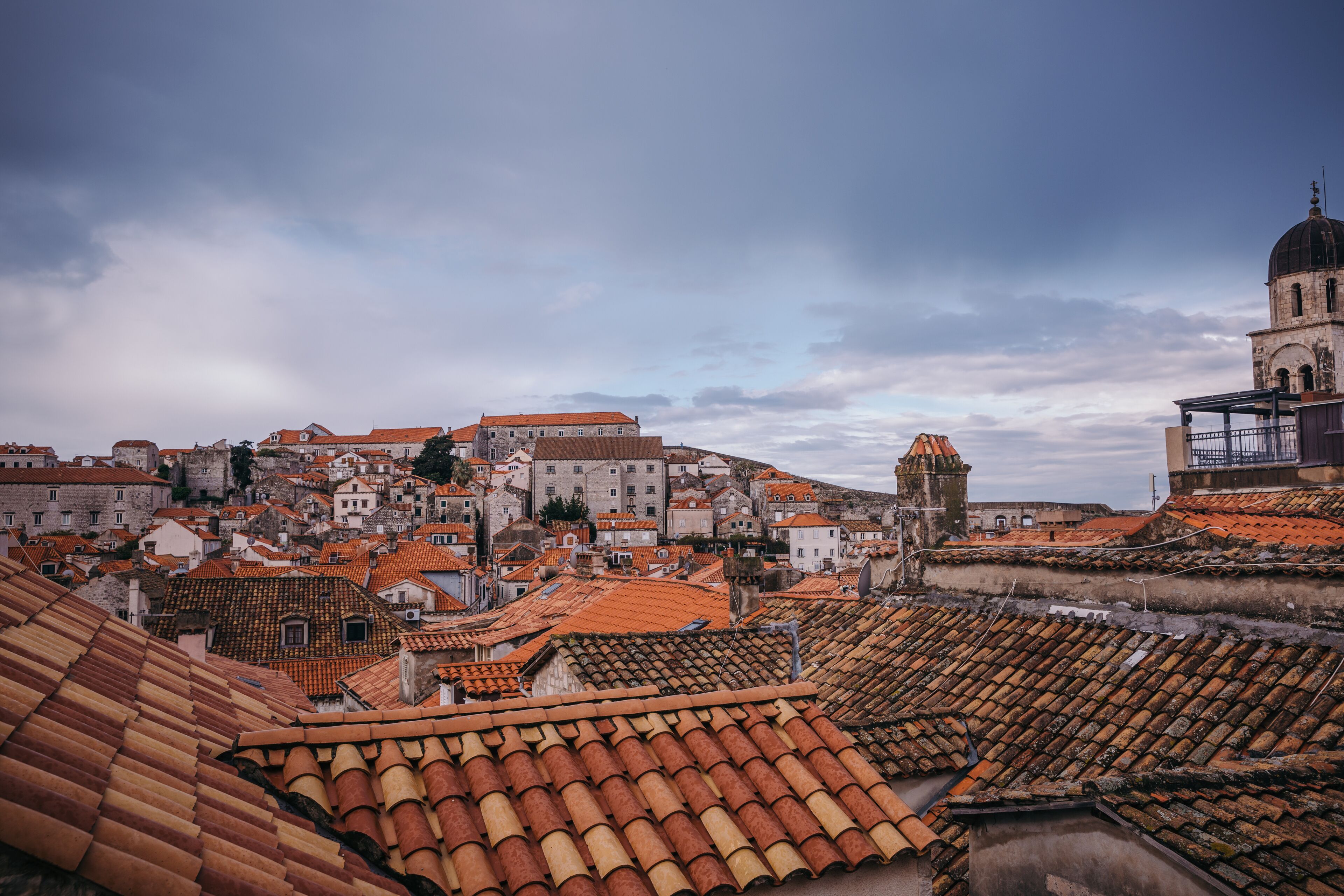 A historic town with terracotta-tiled rooftops and a prominent church with a dome.