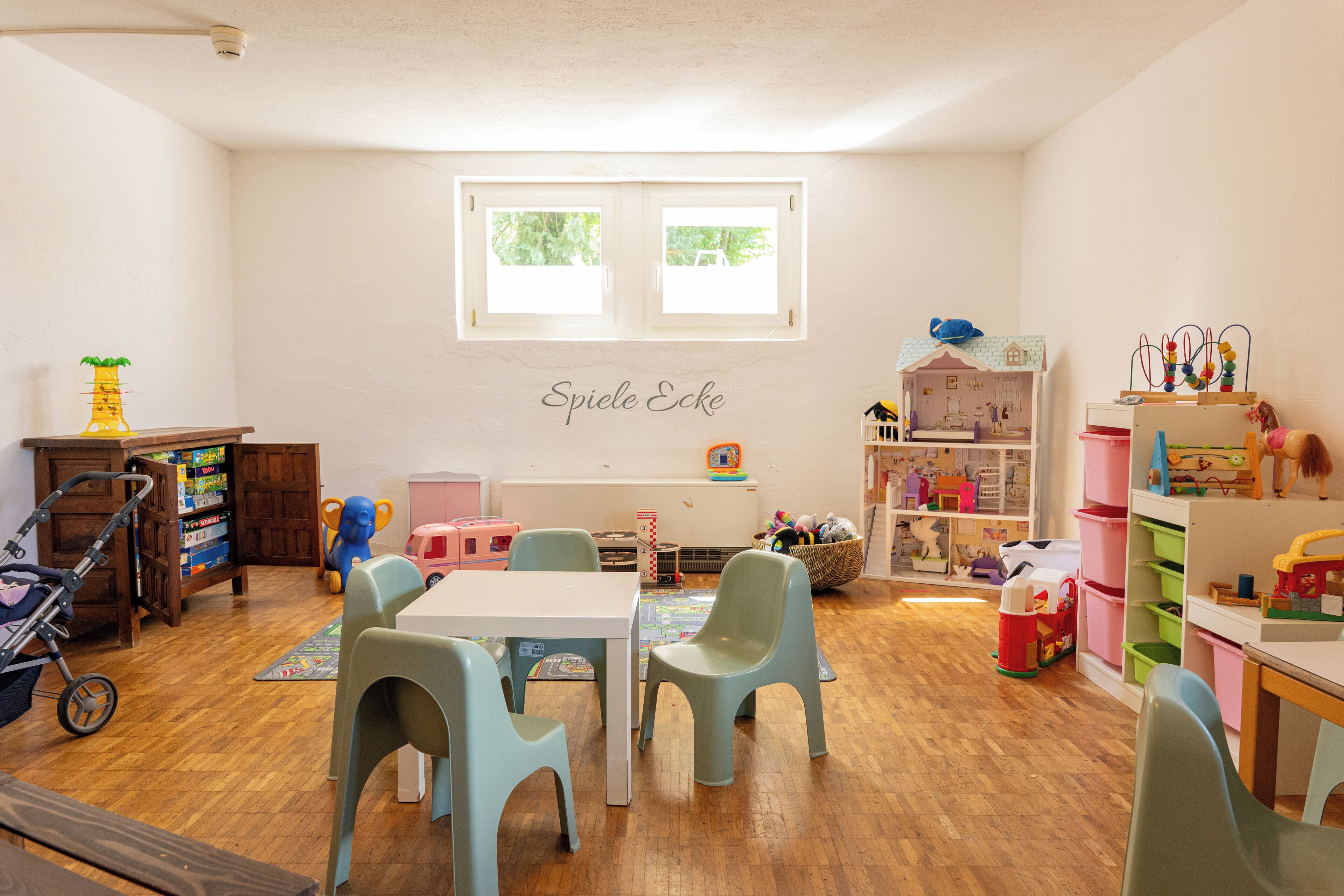 Ein Spielzimmer für Kinder mit Tisch, Stühlen und verschiedenen Spielsachen.