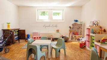 Ein Spielzimmer für Kinder mit Tisch, Stühlen und verschiedenen Spielsachen.
