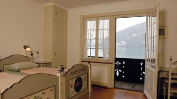 Un dormitorio con cama, escritorio y vista a un lago a través de una ventana.