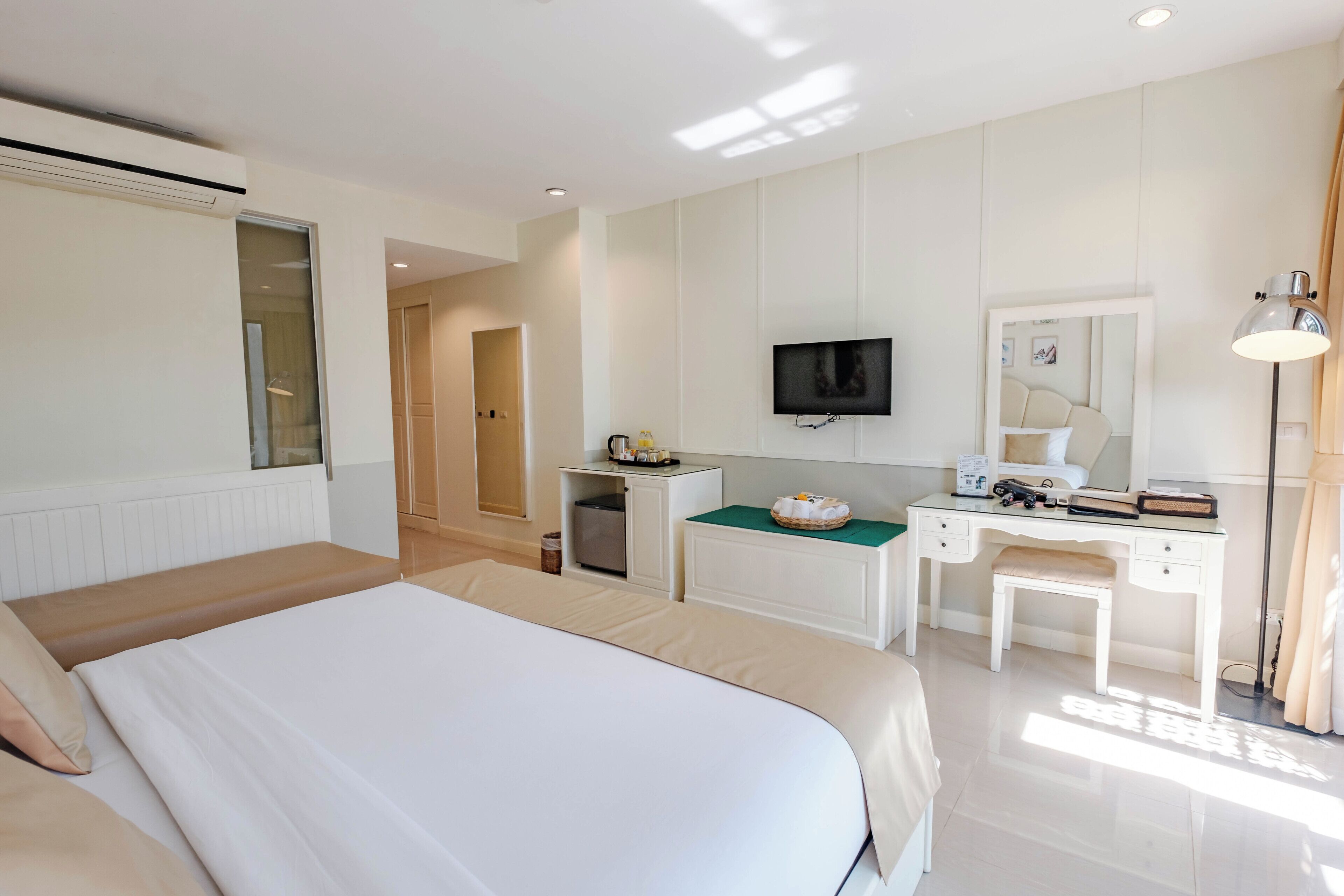 Een hotelkamer met een bed, bureau, televisie en spiegel.