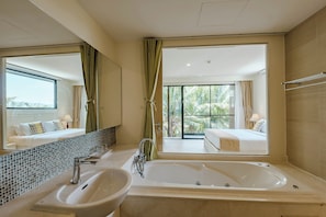 A modern bathroom with a large bathtub, a sink, and a mirror.