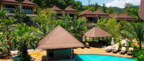 Una piscina al aire libre, sombrillas, sillones reclinables de piscina