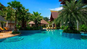 Una piscina al aire libre, sombrillas, tumbonas