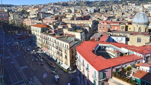 Un paysage urbain mêlant bâtiments historiques et modernes, une rue animée où circulent des voitures, et un ciel bleu dégagé.