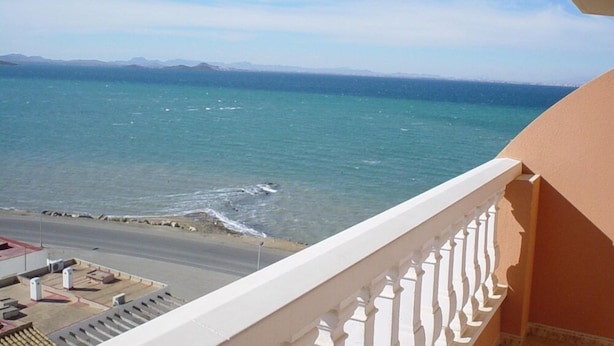 A balcony with a view of the sea and distant mountains. - Isla Grosa Apartamentos (San Javier)