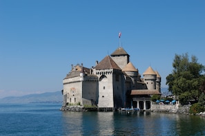 A historic castle with multiple towers, situated on a lakeside. - Youth Hostel Montreux (Montreux)