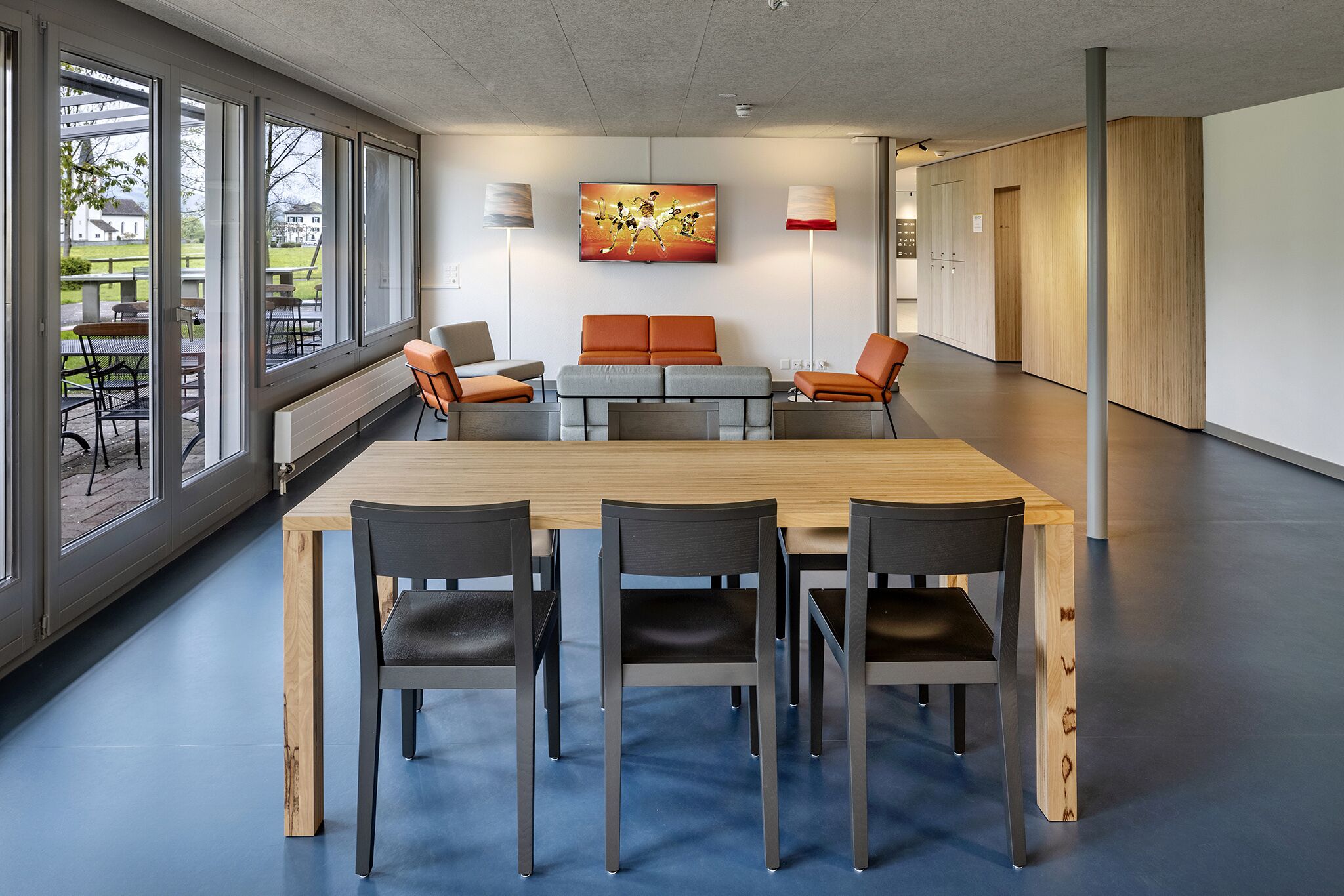 Ein moderner Konferenzraum mit einem großen Tisch, vier Stühlen, einer Couch und einem Gemälde an der Wand.