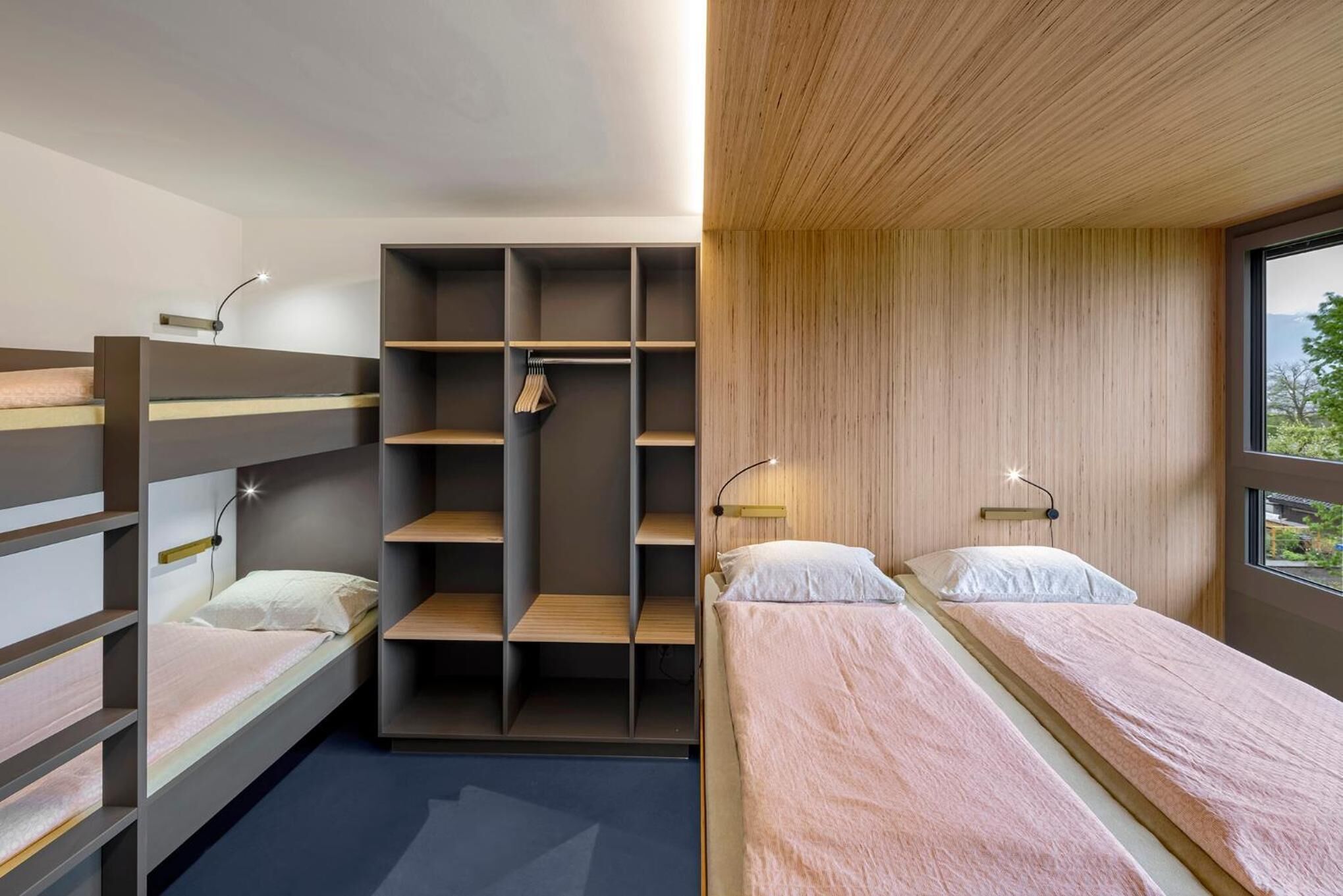 Ein modernes Schlafzimmer mit Etagenbetten, einem eingebauten Kleiderschrank und Nachttischlampen.