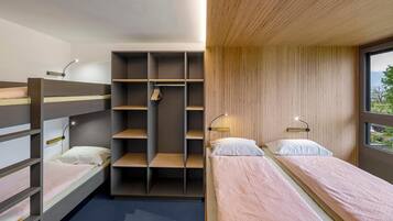 Ein modernes Schlafzimmer mit Etagenbetten, einem eingebauten Kleiderschrank und Nachttischlampen.
