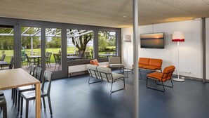 A modern indoor space with a large table and chairs, a sofa, and a TV. - Youth Hostel Rapperswil-Jona (Rapperswil-Jona)