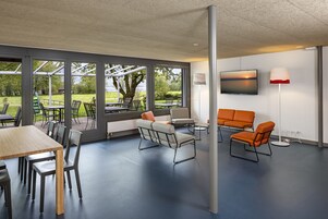Un espacio interior moderno con una mesa grande y sillas, un sofá y un televisor.