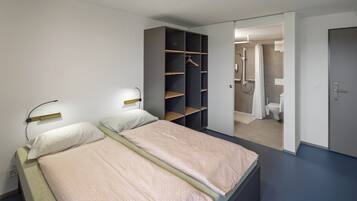 Un dormitorio con dos camas, un armario y un baño visible a través de una puerta abierta.