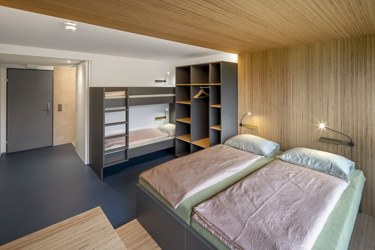 A modern bedroom with bunk beds, built-in shelving, and a minimalist design.
