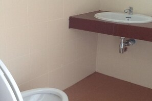 A bathroom with a white toilet, a white sink, and a brown countertop.