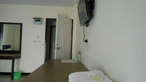 Camera d'albergo con un letto, una TV a parete, uno specchio e una porta che dà su un'altra stanza.