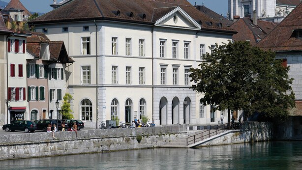 Ein historisches Gebäude mit einer markanten Fassade, Rundbogenfenstern und einem zentralen Eingang.