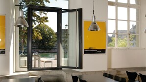 Ein Konferenzraum mit großem Tisch, Stühlen und Blick auf ein Gewässer durch eine Glastür.