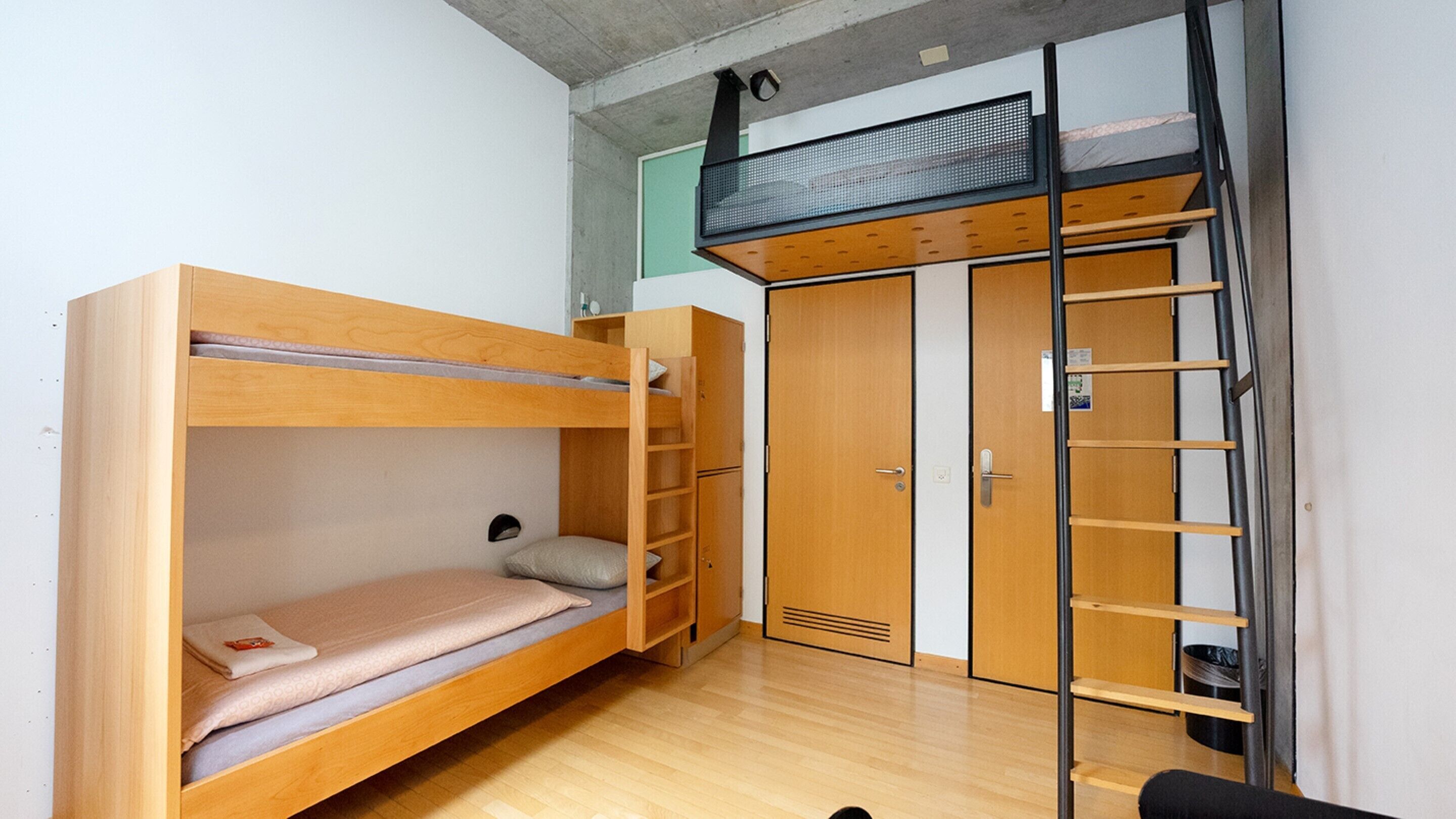 Habitación compacta con literas, un armario y un pequeño escritorio.