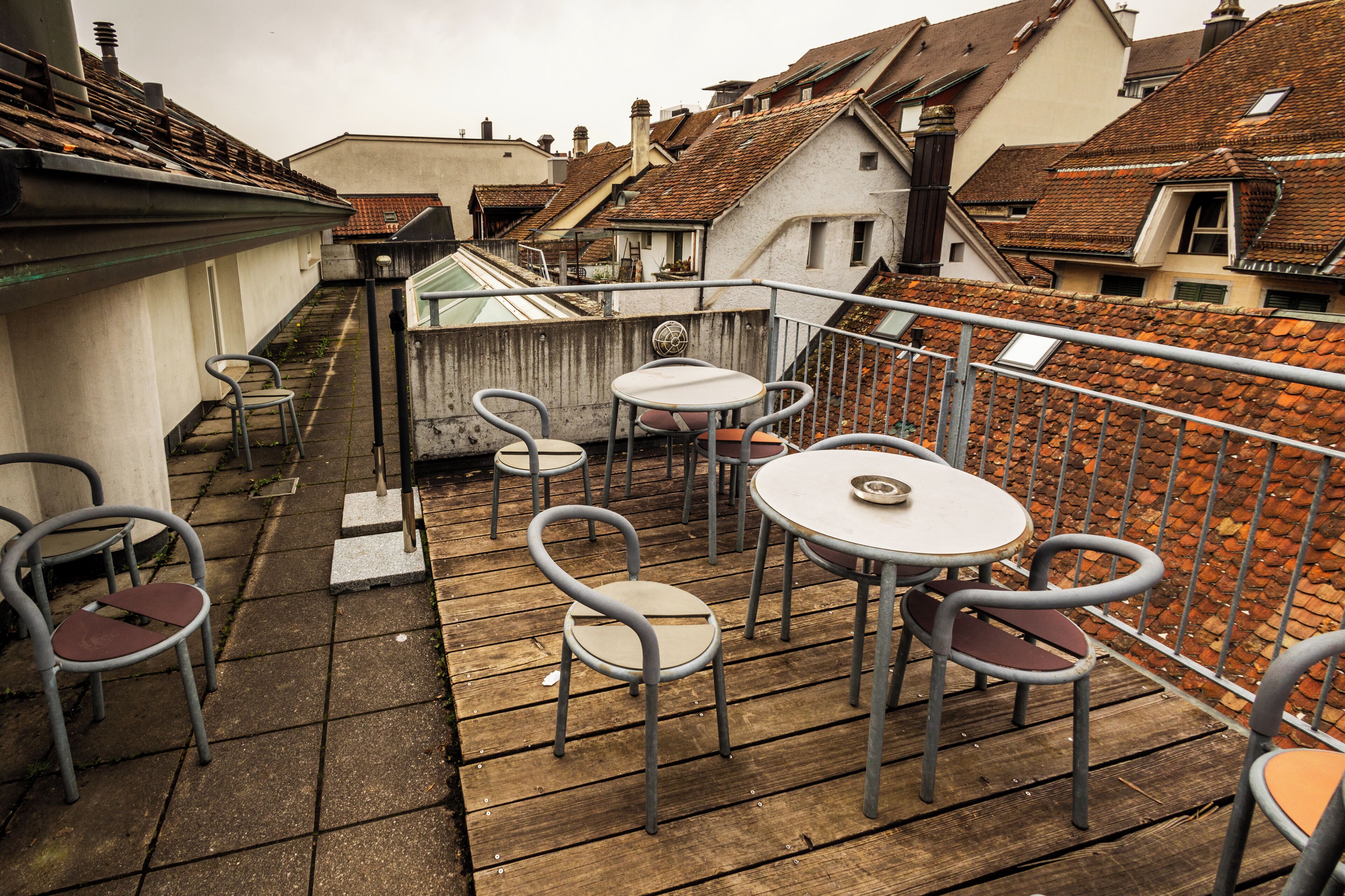 Une terrasse sur le toit, dotée d’un plancher en bois, de chaises et de tables en métal.