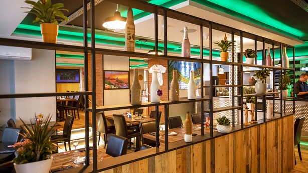 A restaurant with wooden partitions, tables, chairs, and various potted plants. - Cunard Apartments (Douglas)