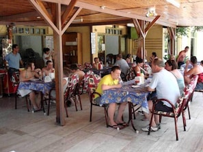 An outdoor dining area with wooden tables and chairs, covered by a wooden roof structure. - Sinem Hotel & Apart (Marmaris)