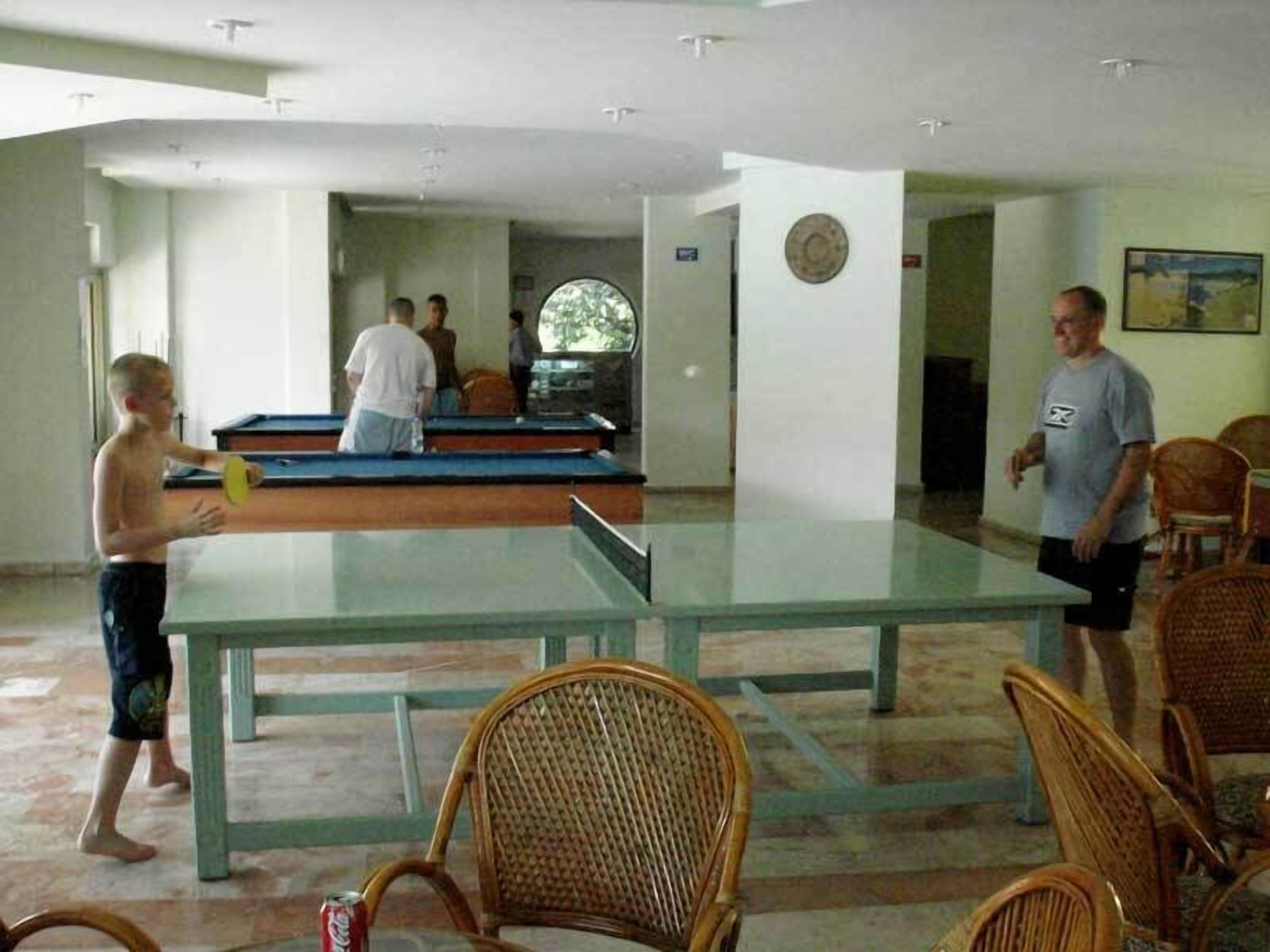 Una mesa de billar en una sala con sillas de mimbre y una mesa de billar.