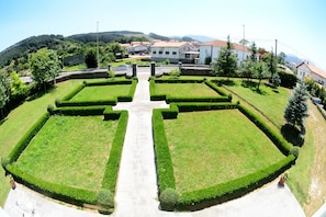 A symmetrical garden with a central pathway leading to a building with multiple windows.