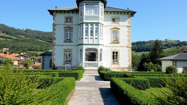 A large, historic building with a central tower, surrounded by well-maintained gardens and a clear view of the countryside. - El Solar del Mazo (Voto)