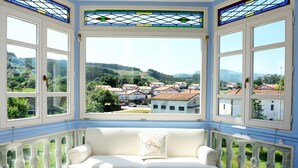 A room with a white sofa and a view of a village through large windows. - El Solar del Mazo (Voto)
