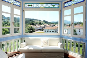 Una habitación con un sofá blanco y vistas a un pueblo a través de amplios ventanales.