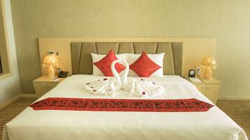 A neatly made bed with a red and white pillow arrangement, a red and black bed runner, and two bedside lamps on wooden nightstands.