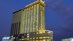 A multi-story hotel with illuminated signage and a prominent wing extending from the main building. - Muong Thanh Luxury Vientiane (Vientiane)