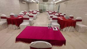 A conference room with multiple tables, each covered with a red tablecloth and white chairs with red sashes. - Kastor International (New Delhi)
