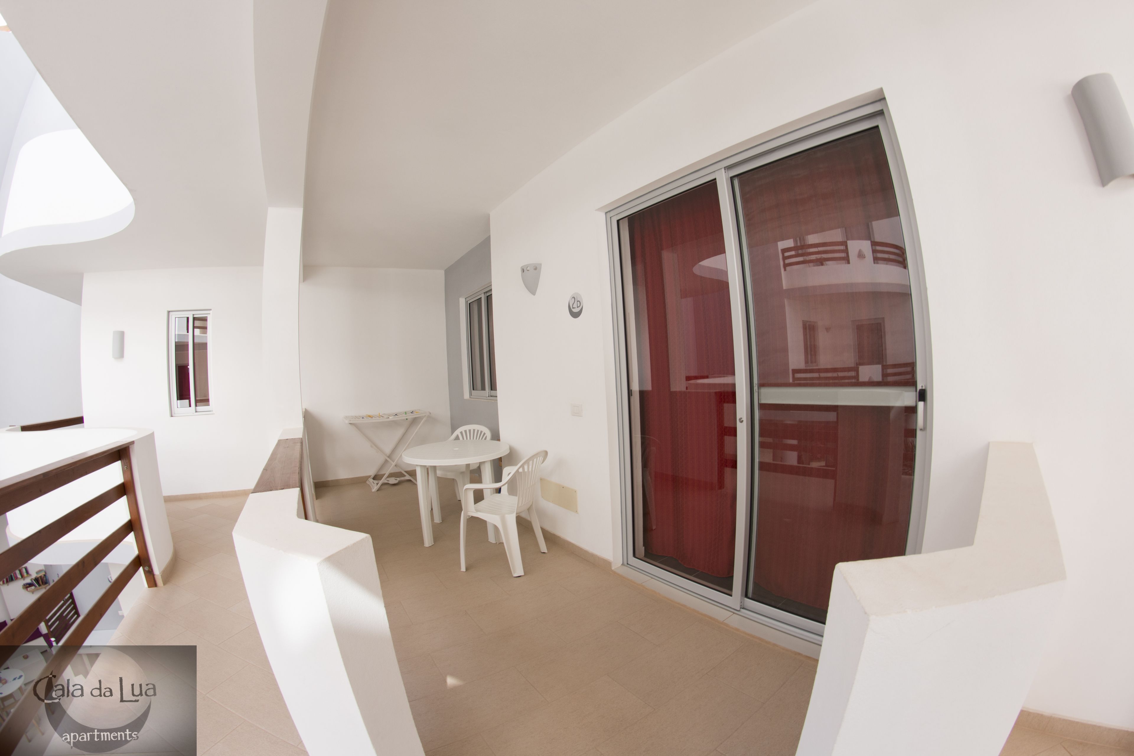 A modern interior with a dining area, a staircase, and a sliding glass door leading to a balcony.