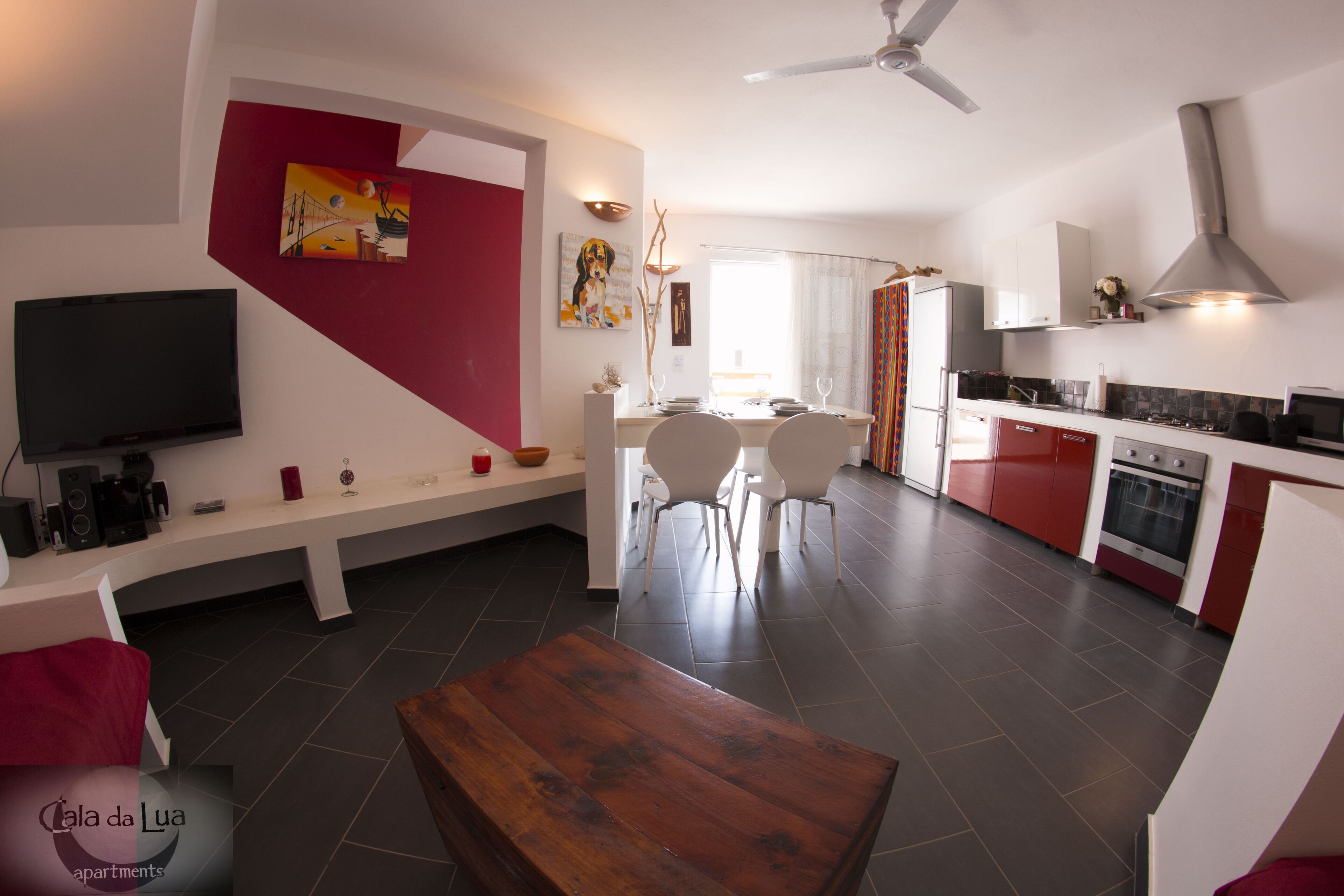 Un salon moderne avec une table basse en bois, un téléviseur et un mur d’accent de couleur rouge.