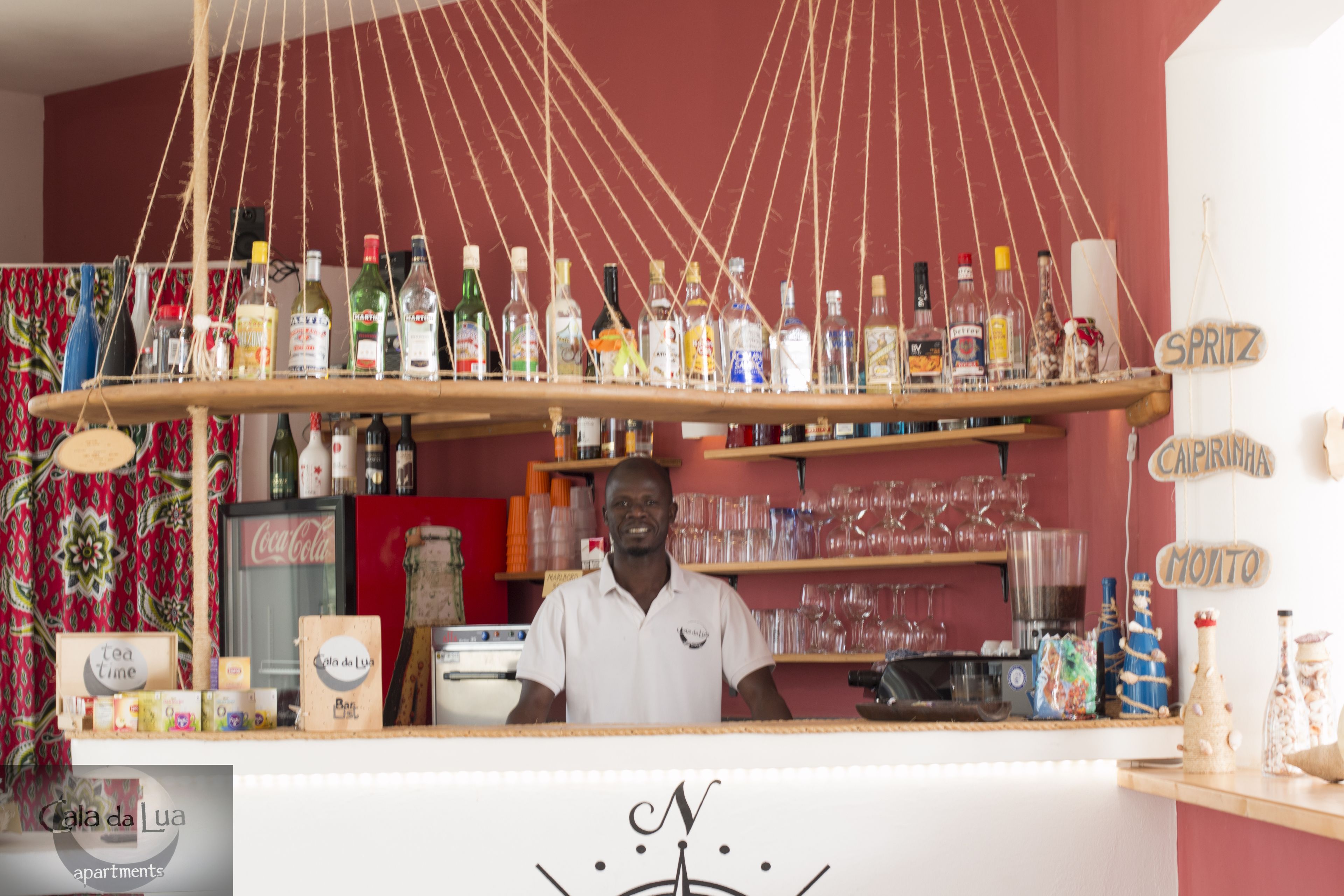 Uma área de bar com diversos frascos e copos expostos.